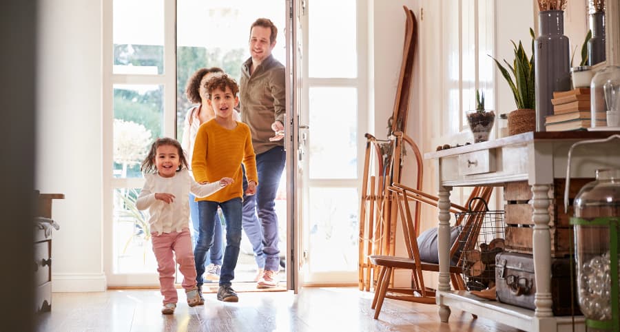 Happy family entering home through front door